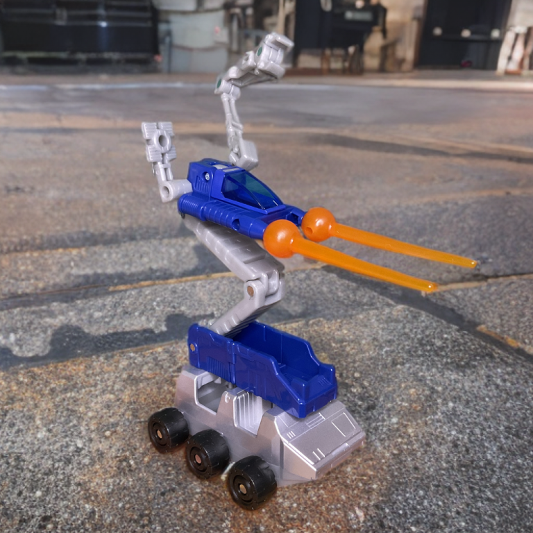 The Studio Series 86-31 trailer in base mode, open to reveal a repair bay with Roller vehicle and Autolauncher Drone, on a grey display stand.