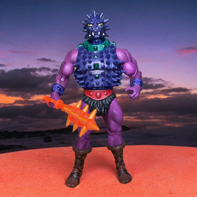 A purple, spike-covered Spikor action figure from the 1985 Masters of the Universe vintage line, wielding a telescoping trident arm, stands against a fiery Eternian backdrop.
