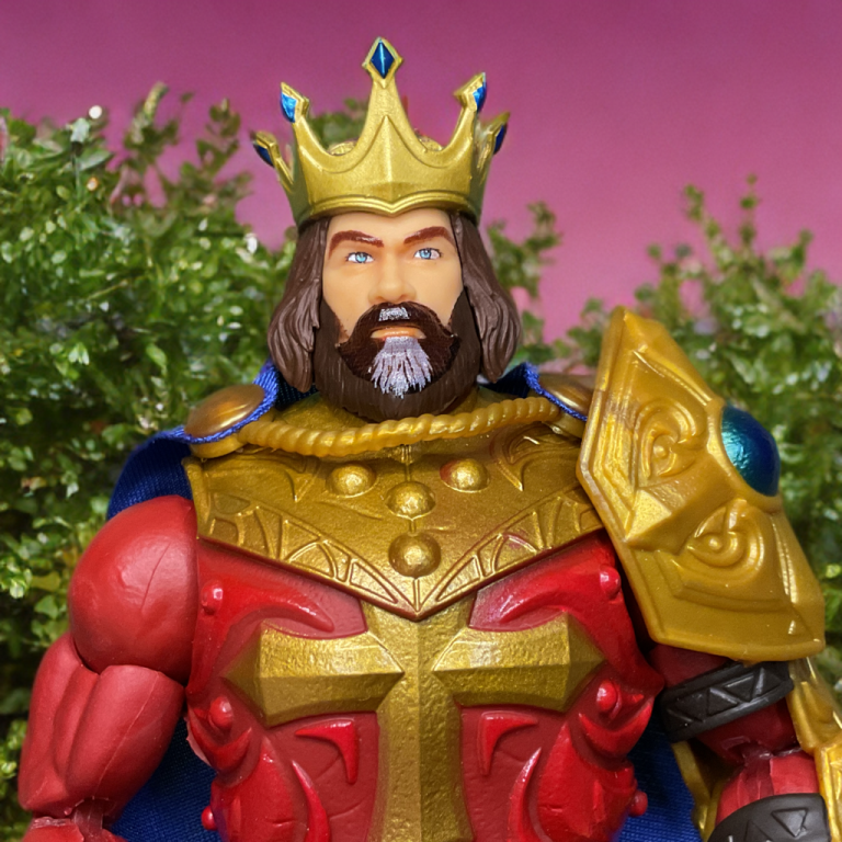 Nahaufnahme der Masterverse-Figur König Randor, die aufwändige blaue Juwelendetails an der Krone, dem Zepter und der Rüstung zeigt, mit einem weichen roten Umhang dahinter.