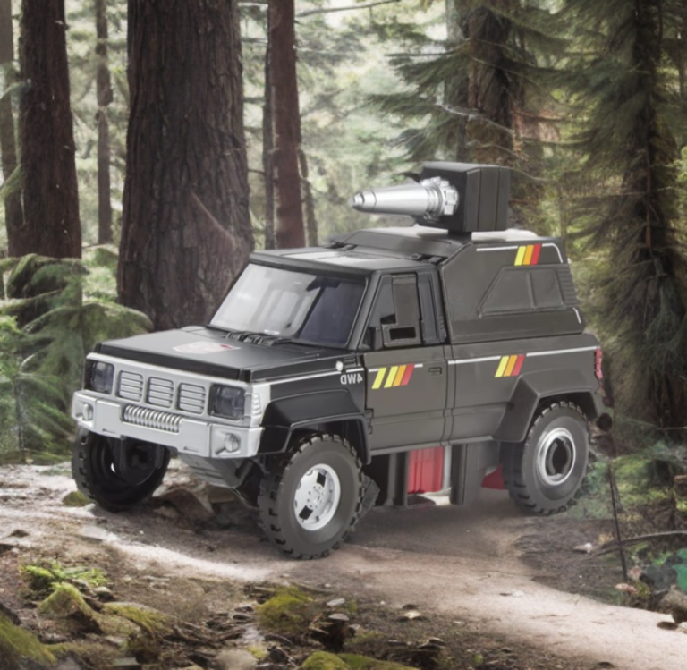 Trailbreaker in camper truck mode, parked on a rocky Earth terrain with silver wheels and red taillights highlighted, subtly showing the backpack’s canopy to hint at the hidden gadgets without focusing on them.
