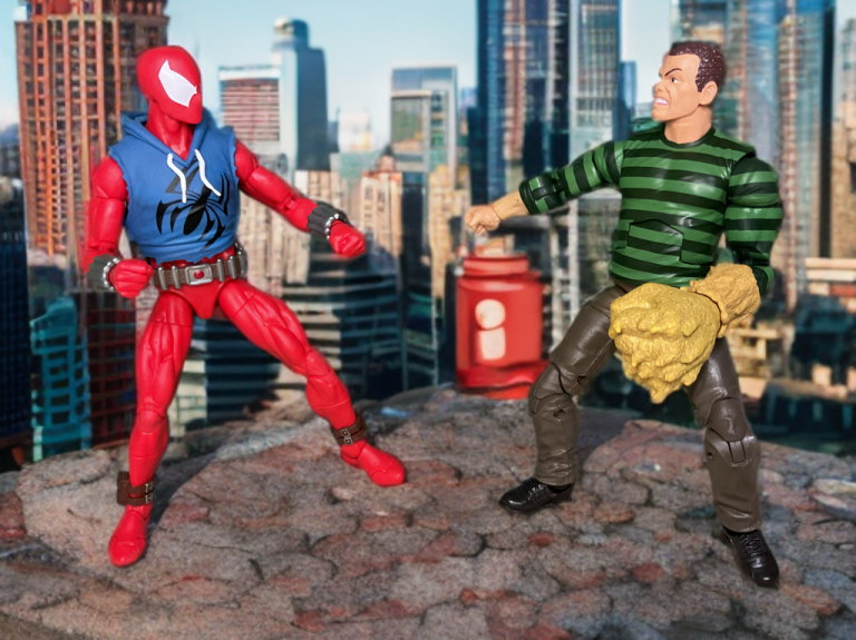 La figurine Sandman Retro 2025 fait face à une figurine Scarlet Spider, avec des pièces à effet de sable éparpillées, évoquant un affrontement classique de bande dessinée.