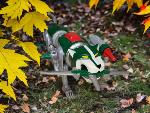 The Green Lion from Playmates’ Voltron set rests in a lush forest setting, its vibrant color and posable joints emphasized.