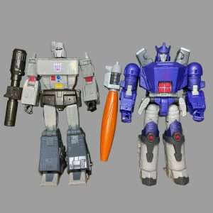 A side-by-side view of Studio Series Leader Class Megatron and Studio Series 86-31 Leader Class Galvatron in robot mode, showcasing their distinct color schemes and designs against a neutral background.
