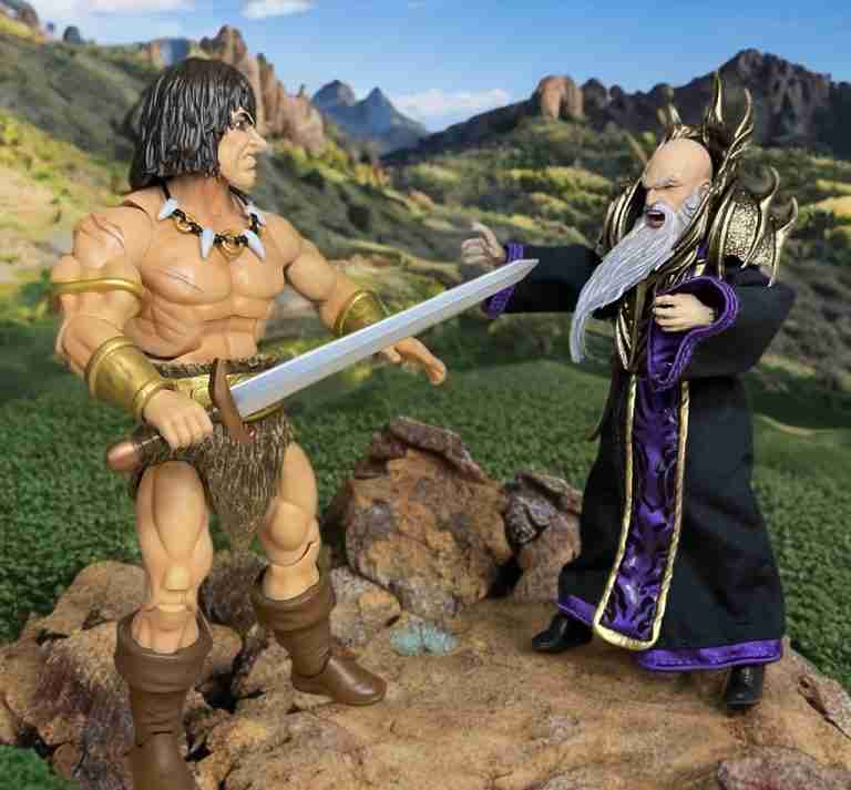 Conan charges with broadsword toward robed wizard Arrizak in a mountain backdrop.