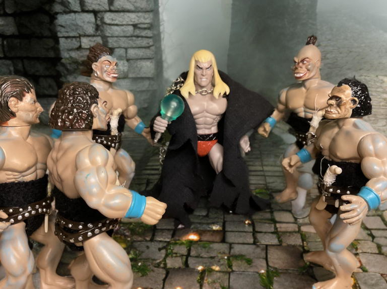 Nekrus holding glowing orb, surrounded by grotesque Flesh Eaters in dimly lit stone chamber.