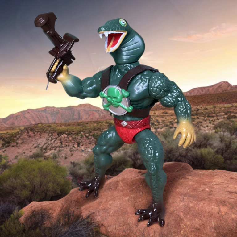 King Kobra, o guerreiro serpente verde com blaster, em pé em uma rocha vermelha em meio a montanhas desérticas ao pôr do sol.
