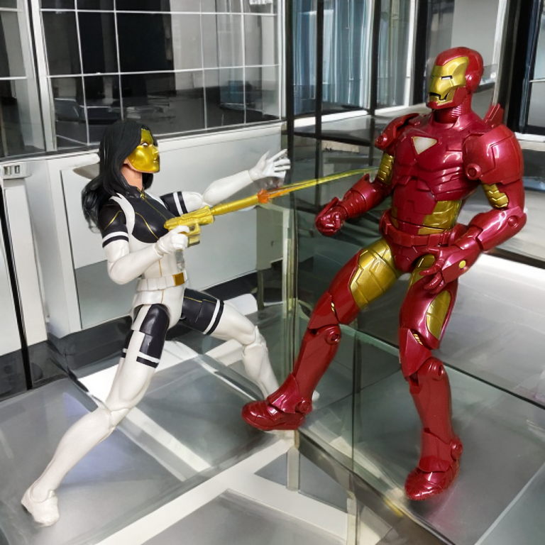 Madame Masque figure with a golden mask and auburn hair, holding a translucent orange blast effect accessory, posed next to an Iron Man figure.