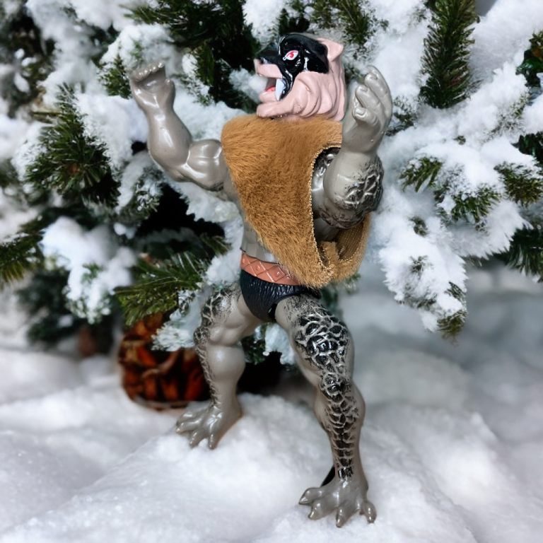 Guerrero Lobo, la figura gris enmascarada con cuello de piel, erguida en un bosque cubierto de nieve.