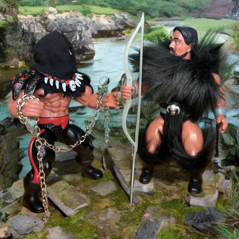 Pose serena, porém conflituosa, em um riacho exuberante com luz natural suave: Grym à esquerda com capa esfarrapada e machado, de frente para Ulysses à direita com bigode, corpo musculoso e arco branco na capa preta.