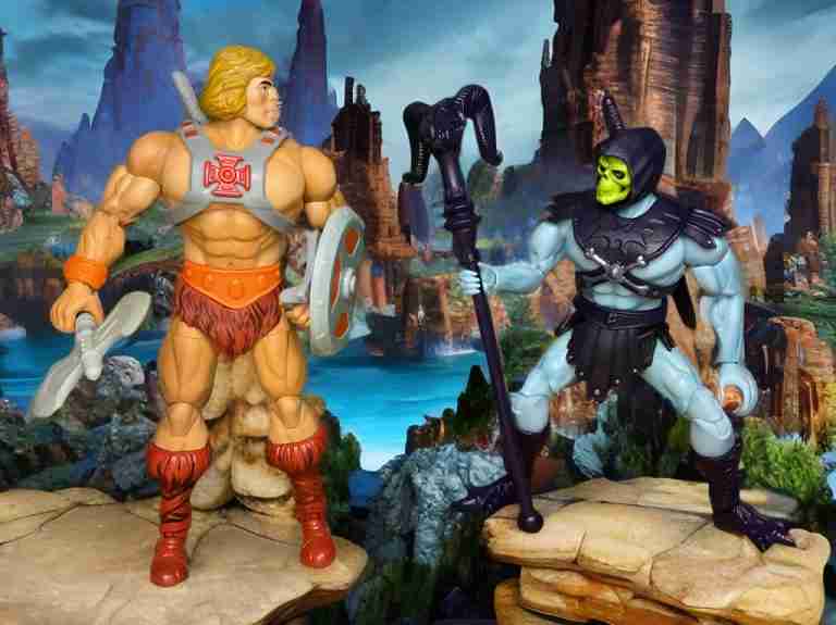 Skeletor mit seinen Krallenfüßen und seinem gezackten Schwert steht in einem Totenkopf-Lager und wirkt dunkle Magie, während He-Man sich mit seinem Schild in der Hand auf einen Gegenangriff in einer felsigen Schlucht vorbereitet.