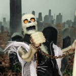 Archterrus, an undead skeleton with a glowing shroud, stands victorious in a foggy graveyard, staff planted, in Zoloworld’s 2025 Realm of the Underworld photoshoot.