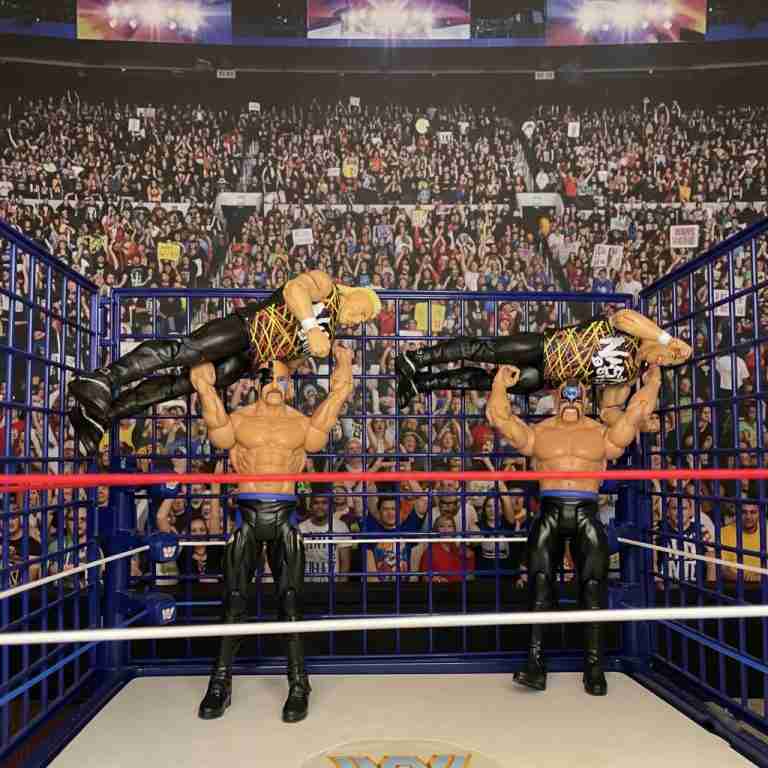 Actionfiguren der Road Warriors Hawk und Animal, die die Power Slams an den Nasty Boys in einem blauen Stahlkäfig im Ring vor einer Zuschauerkulisse ausführen.