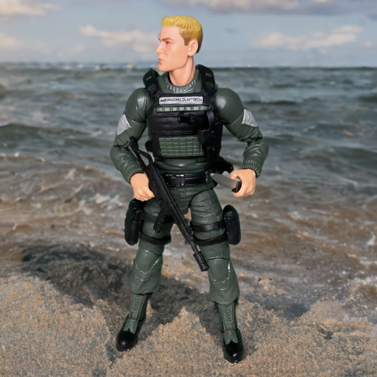 Hawk’s 6.25-inch figure, wearing a green jacket, poses on the beach in front of the ocean.