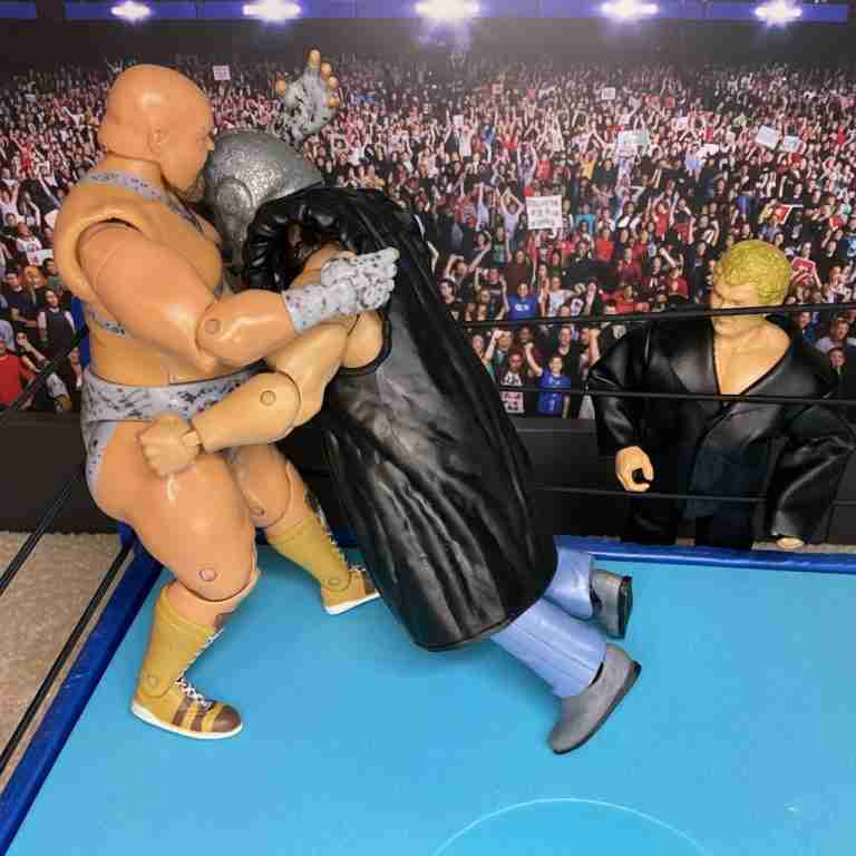 Die Shockmaster-Actionfigur stößt Bastion Booger in die Ecke des Turnbuckles, während Harley Race überrascht zuschaut.
