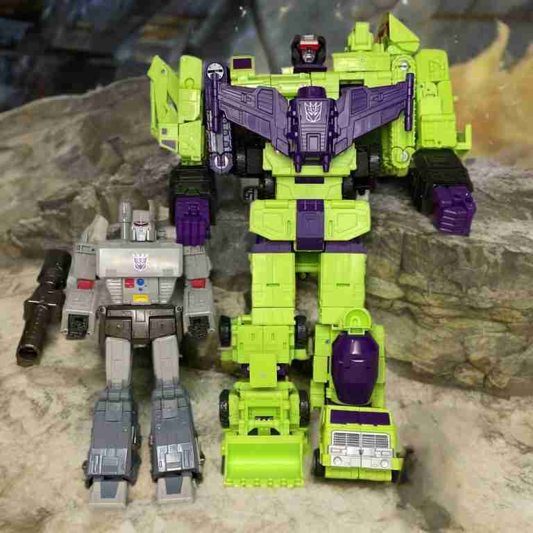 Seite-an-Seite-Vergleich: Studio Series ’86 Devastator gegen Studio Series 86 Megatron. Der Größenunterschied wird hervorgehoben.