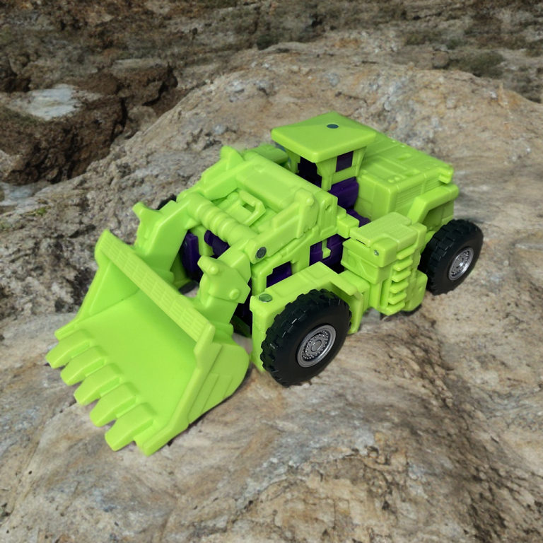 Scavenger front-end loader scooping a small toy, treads gripping surface, highlighting purple accents in the ’86 Constructicon design.