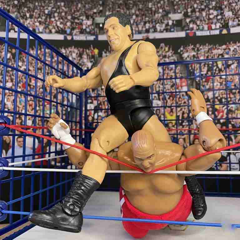 Andre the Giant hebt Abdullah the Butcher während eines simulierten Stahlkäfig-Kampfes im Würgegriff über die Seile.