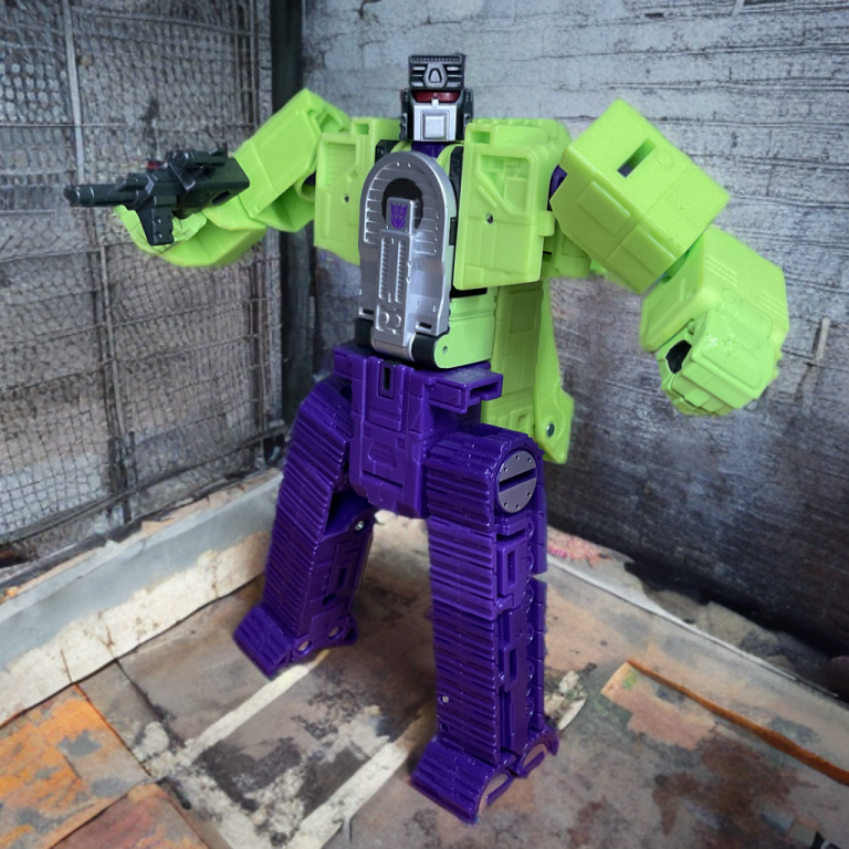 Close-up of Hook’s drill arm in robot mode, showcasing red accents and scowling face from Hasbro’s ’86 movie-accurate Voyager-class toy.
