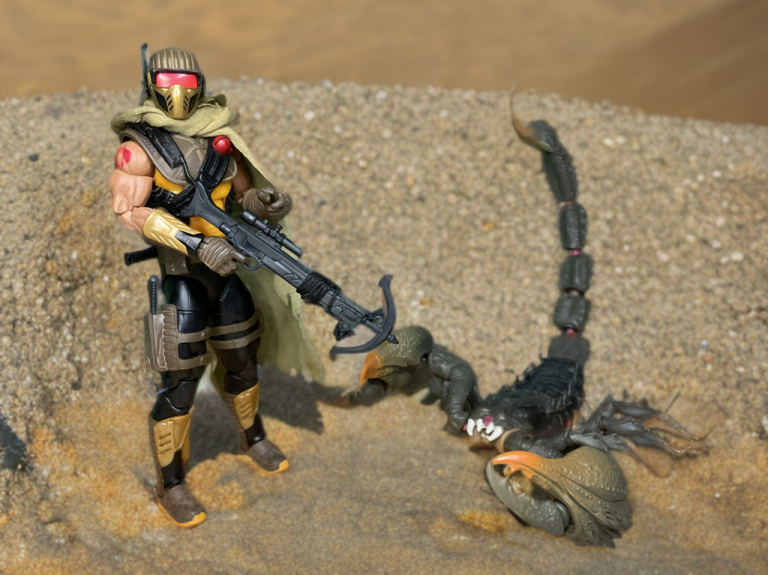 A G.I. Joe Classified Series #180 Cobra Desert Scorpion figure stands in a sandy diorama, gripping a crossbow, with the colossal SKRP10N-25 mutant scorpion poised beside it.