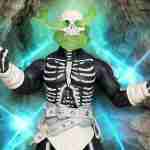 The Head Hunter figure posed in a rocky cave with glowing green spectral energy swirling around its skull head.