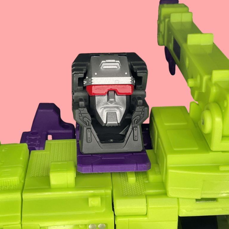 Devastator’s head detail, derpy grin and yellow eyes glowing, straight from the ‘86 movie’s stop-motion charm in Hasbro’s plastic form.