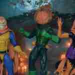 En un bosque sombrío junto a un viejo puente, la máscara diabólica de Hallow's Eve, la sonrisa de duende de Hobgoblin y la cabeza llameante de Jack O'Lantern brillan entre calabazas talladas, sus poses dinámicas y sus vibrantes trajes crean un amenazador retablo de Halloween contra árboles retorcidos.