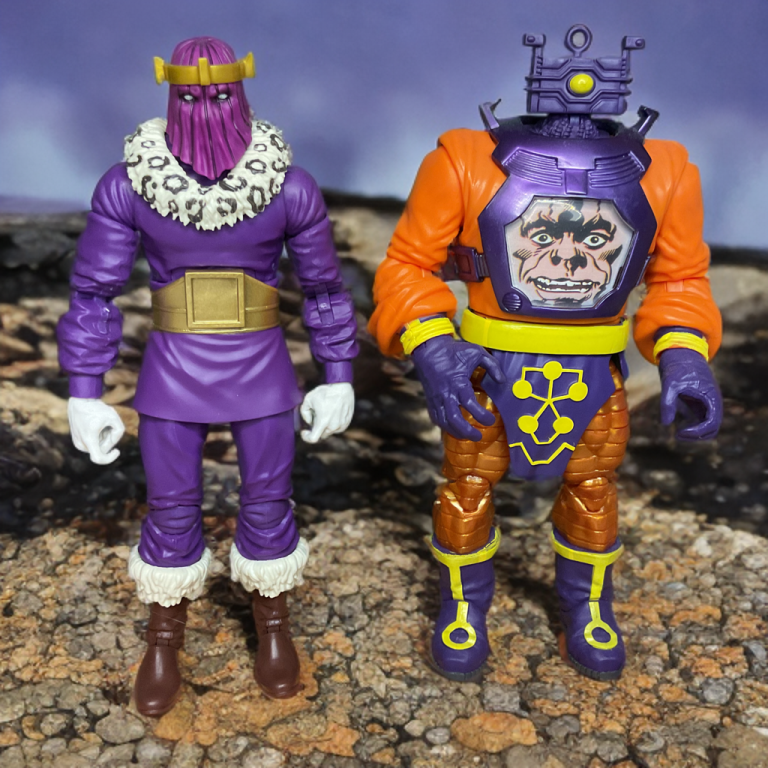 Action pose of Zemo gesturing commandingly beside Zola's top-heavy robotic form in a villain lair setting.