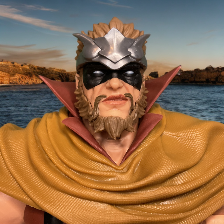 Close-up of Gorgon’s portrait – angry grimace, thick black beard, red headband, and intense eyes staring straight ahead