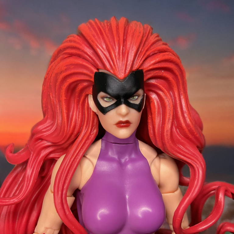 Close-up of Medusa’s face sculpt: imperious expression, purple mask, and massive red prehensile hair flowing dramatically outward.