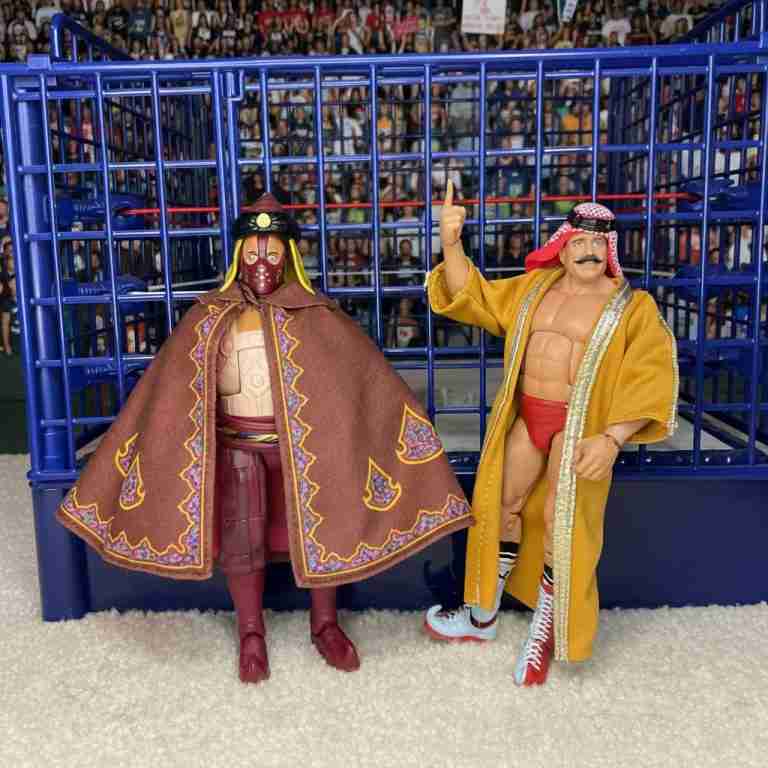 Iron Sheik leads masked Sultan down ramp toward steel cage.